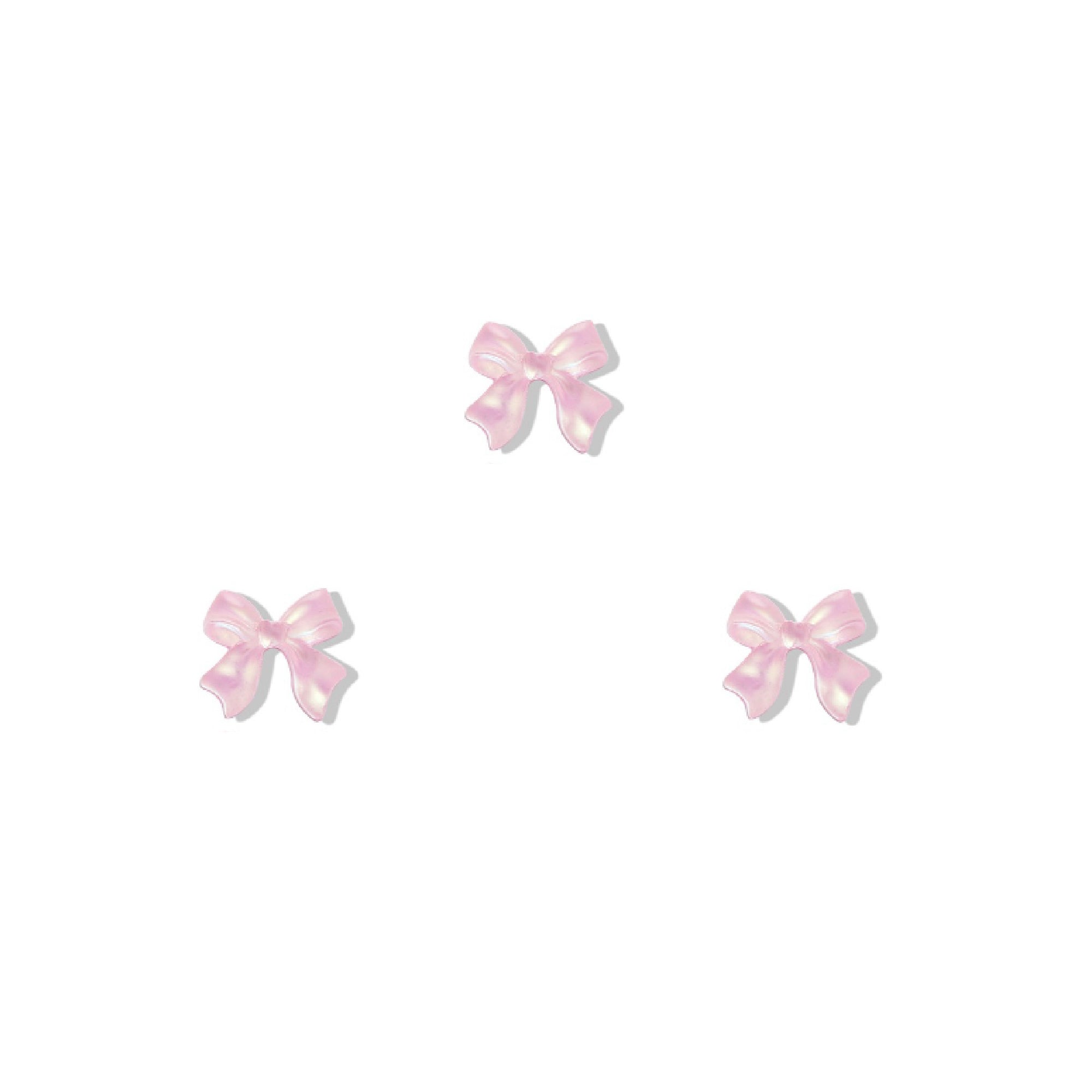 Set of three pink bow-shaped nail charms on a white background