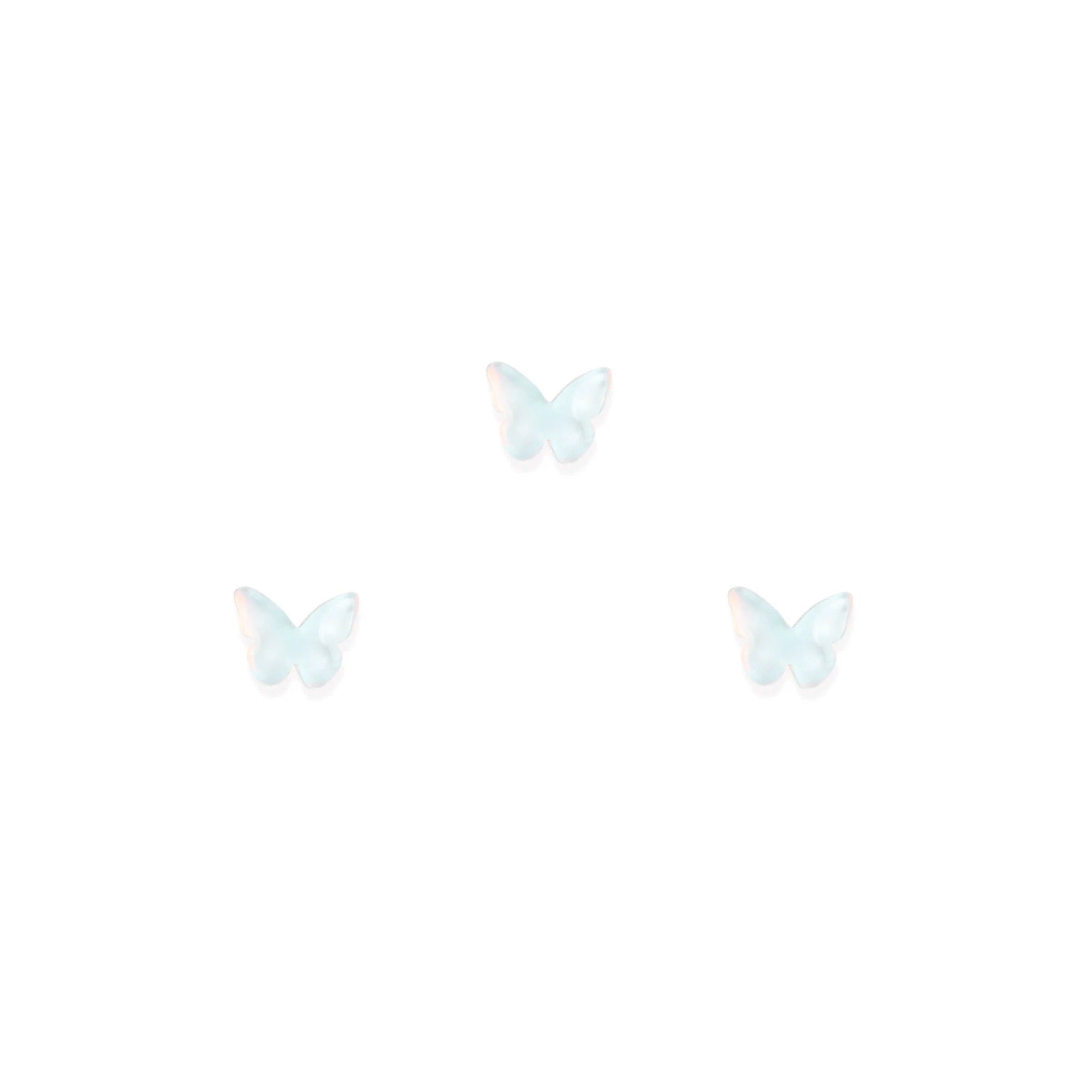 Three white butterfly-shaped nail charms on a white background